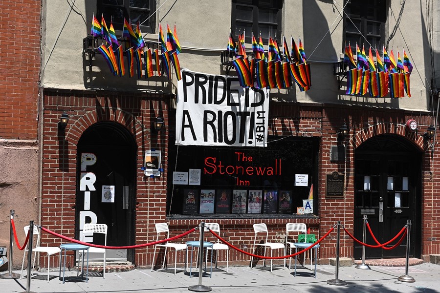 Stonewall building with a sign that reads "Pride's a Riot" 