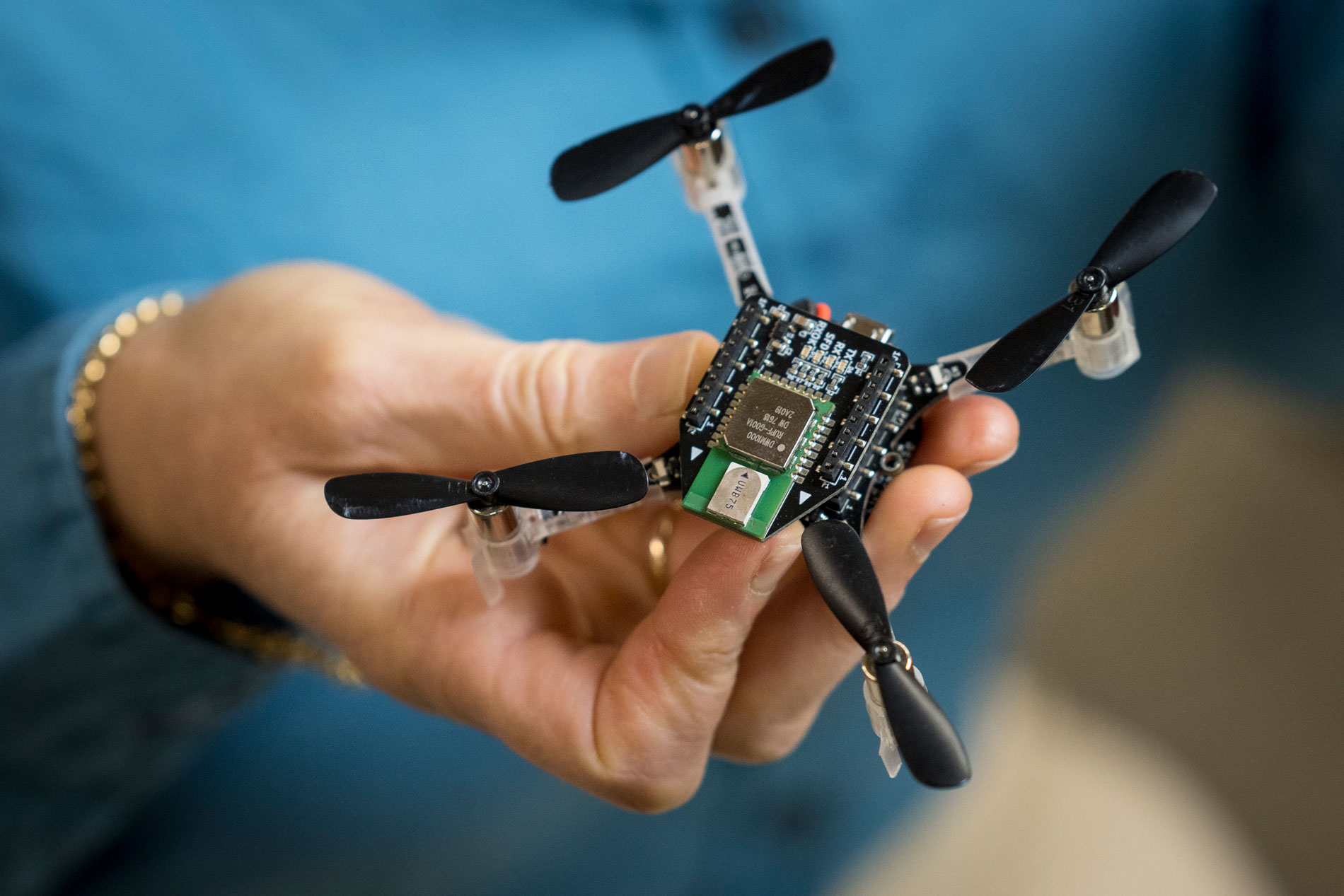 A person holding a small drone with propellers